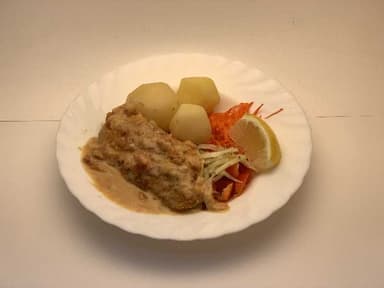 Fiskfilé i het sås serveras med kokt potatis samt måltidstillbehör