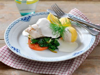 Pocherad fisk i vitvinssås serveras med brynta champinjoner och kokt potatis